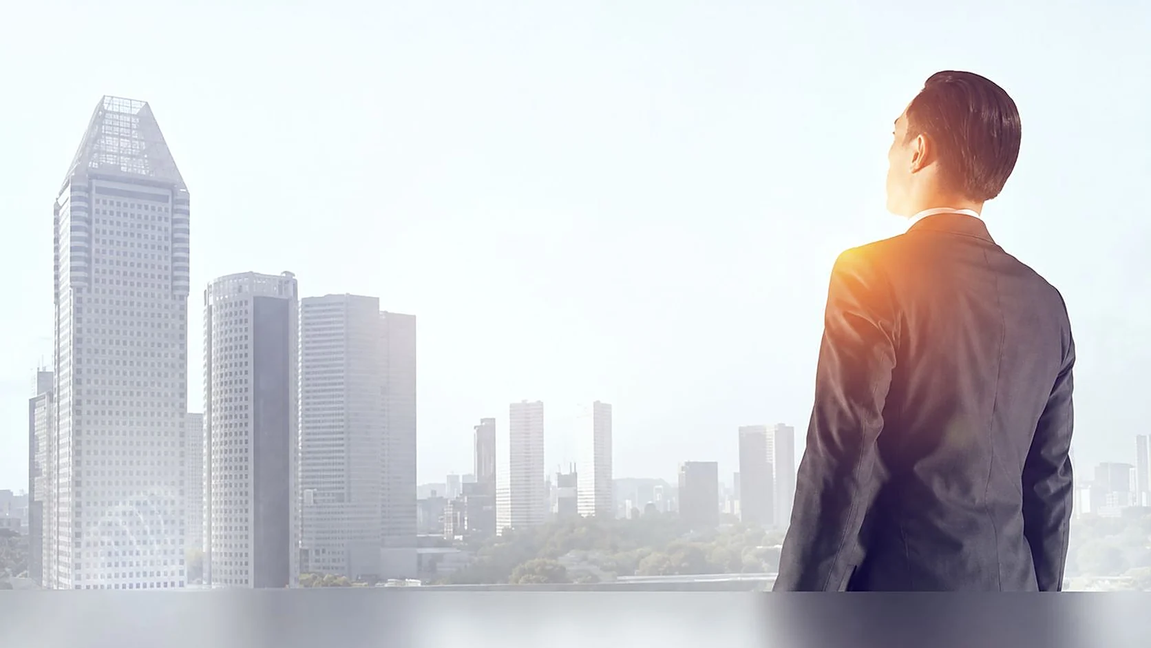 A man in a suit standing with his back to camera, looking out over the Doha skyline.